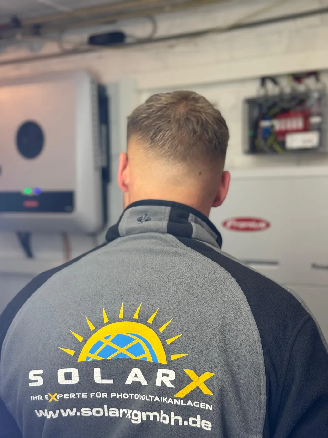 SolarX Monteur bei der Inbetriebnahme einer Photovoltaikanlage SolarX-Monteur nimmt die Fronius-Anlage in Betrieb und prüft die Anschlüsse