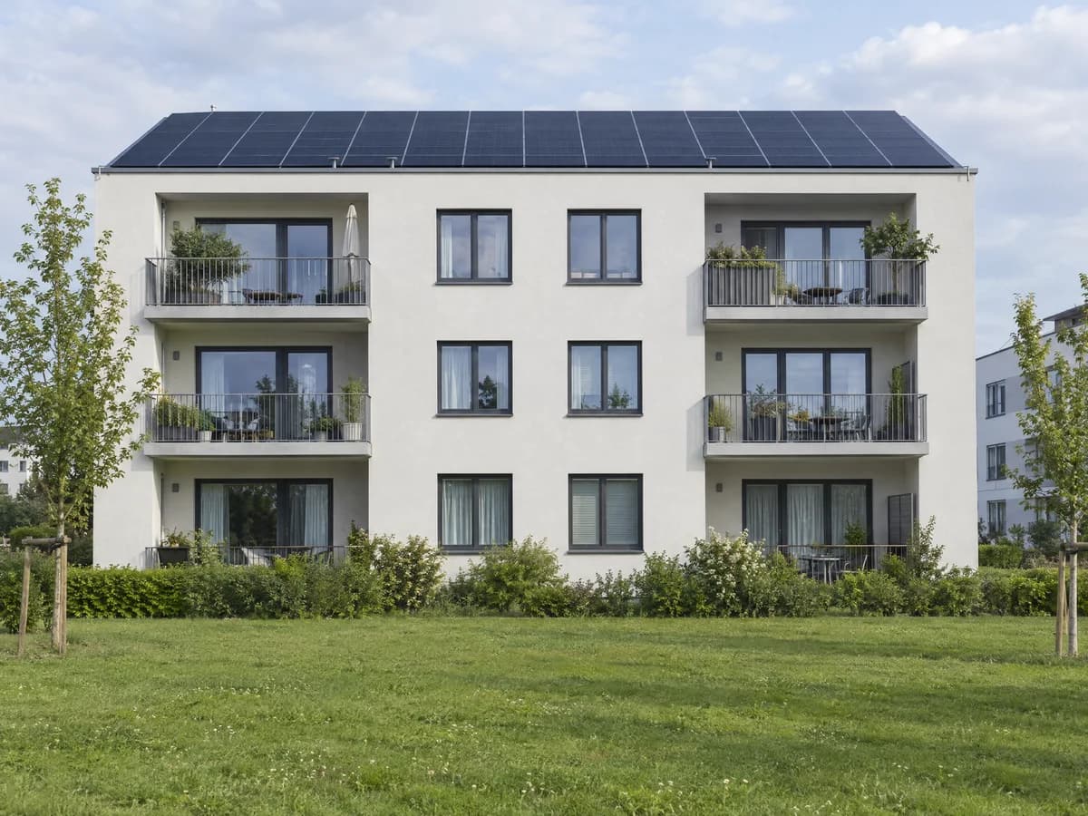 SolarX – Mehrfamilienhaus mit Balkonen und Solardach Mehrfamilienhaus mit Balkonen und schwarzen Solarmodulen auf dem Dach