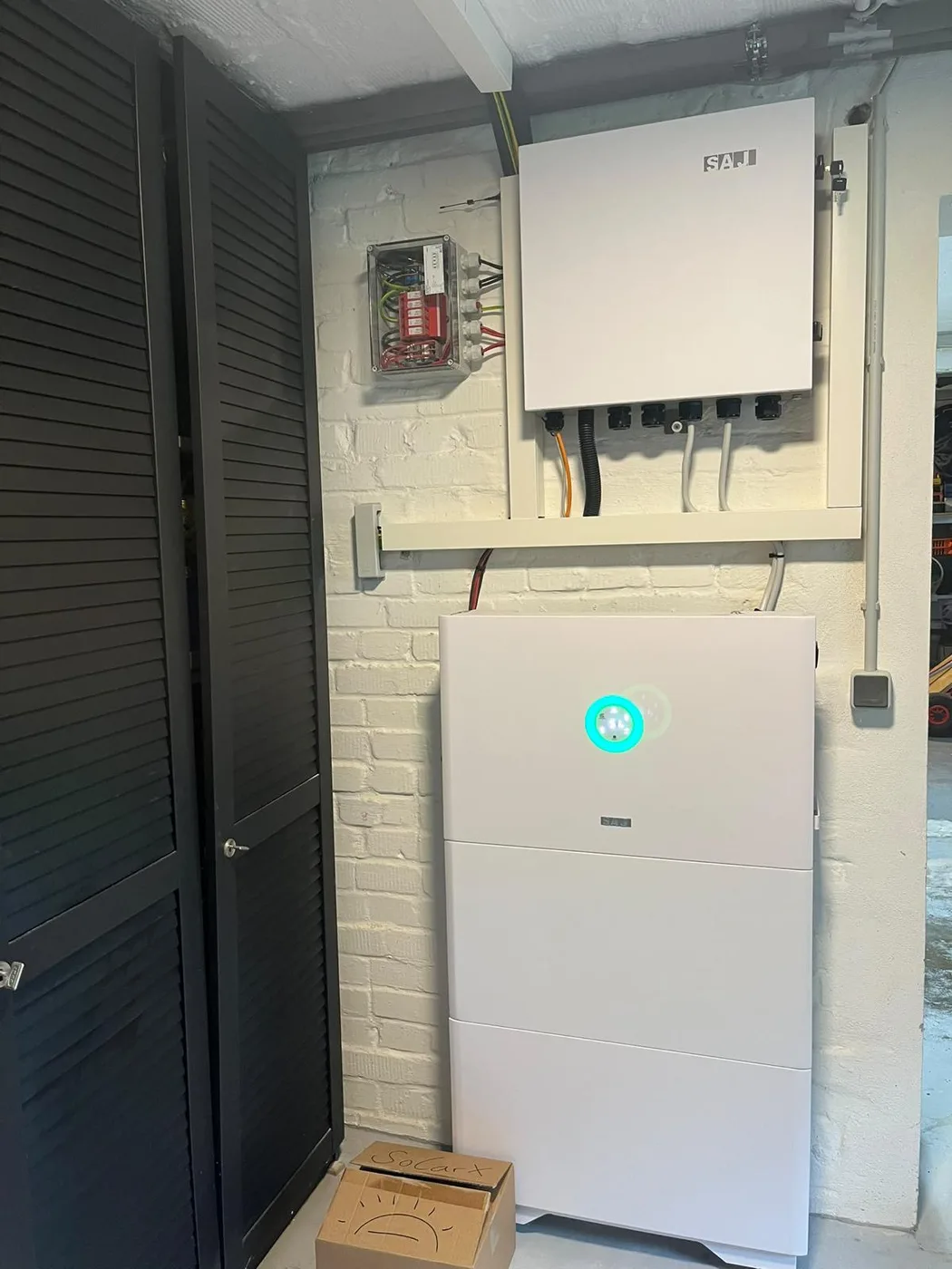 Photovoltaik-Referenz SolarX – Speicher, Wechselrichter und Zähler im Keller SolarX Referenz: Batteriespeicher mit grünem Statusring an einer weiß gestrichenen Kellerwand, darüber der Wechselrichter und der Zählerkasten